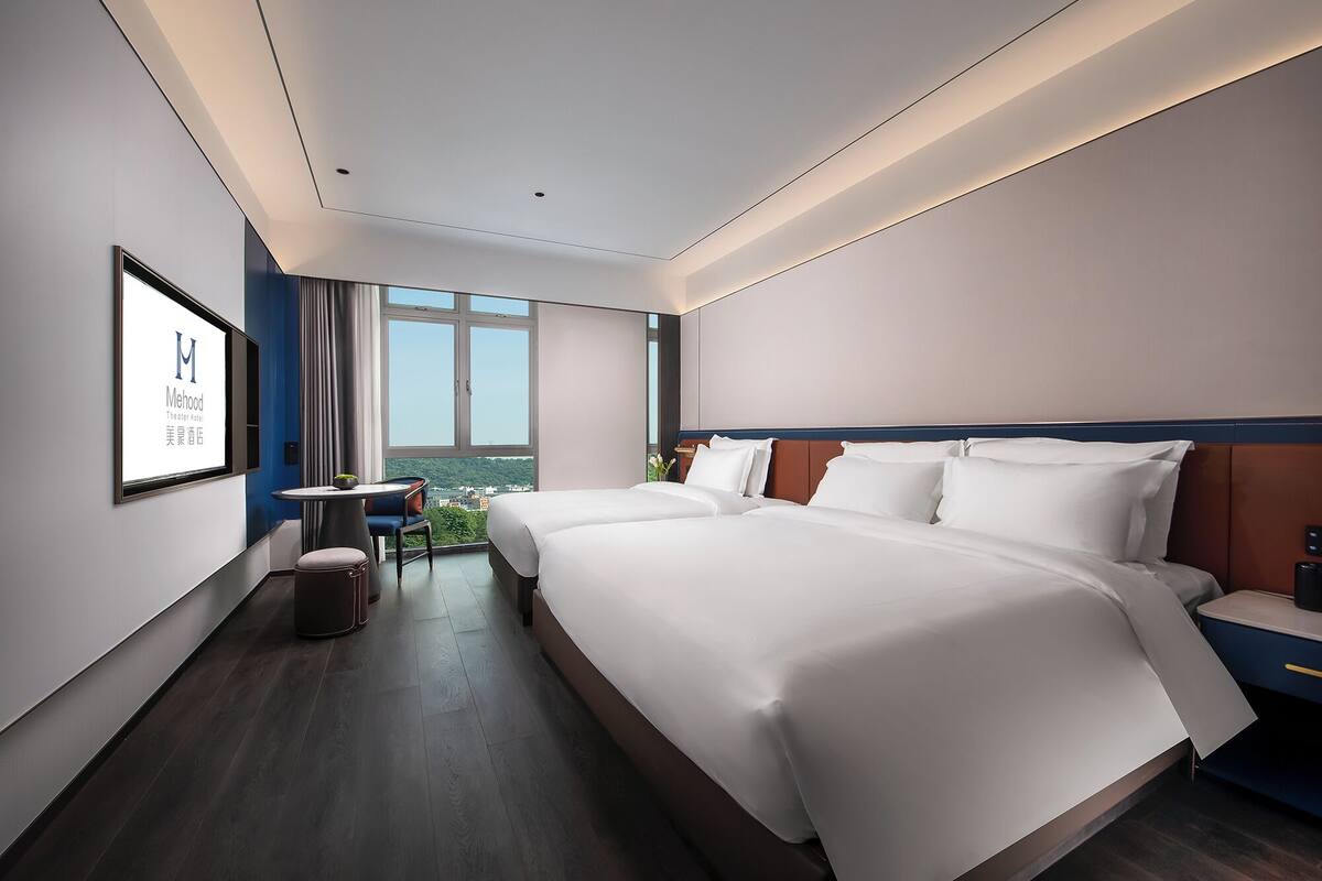 Una habitación de hotel con una cama grande, un escritorio y vistas a la ciudad.