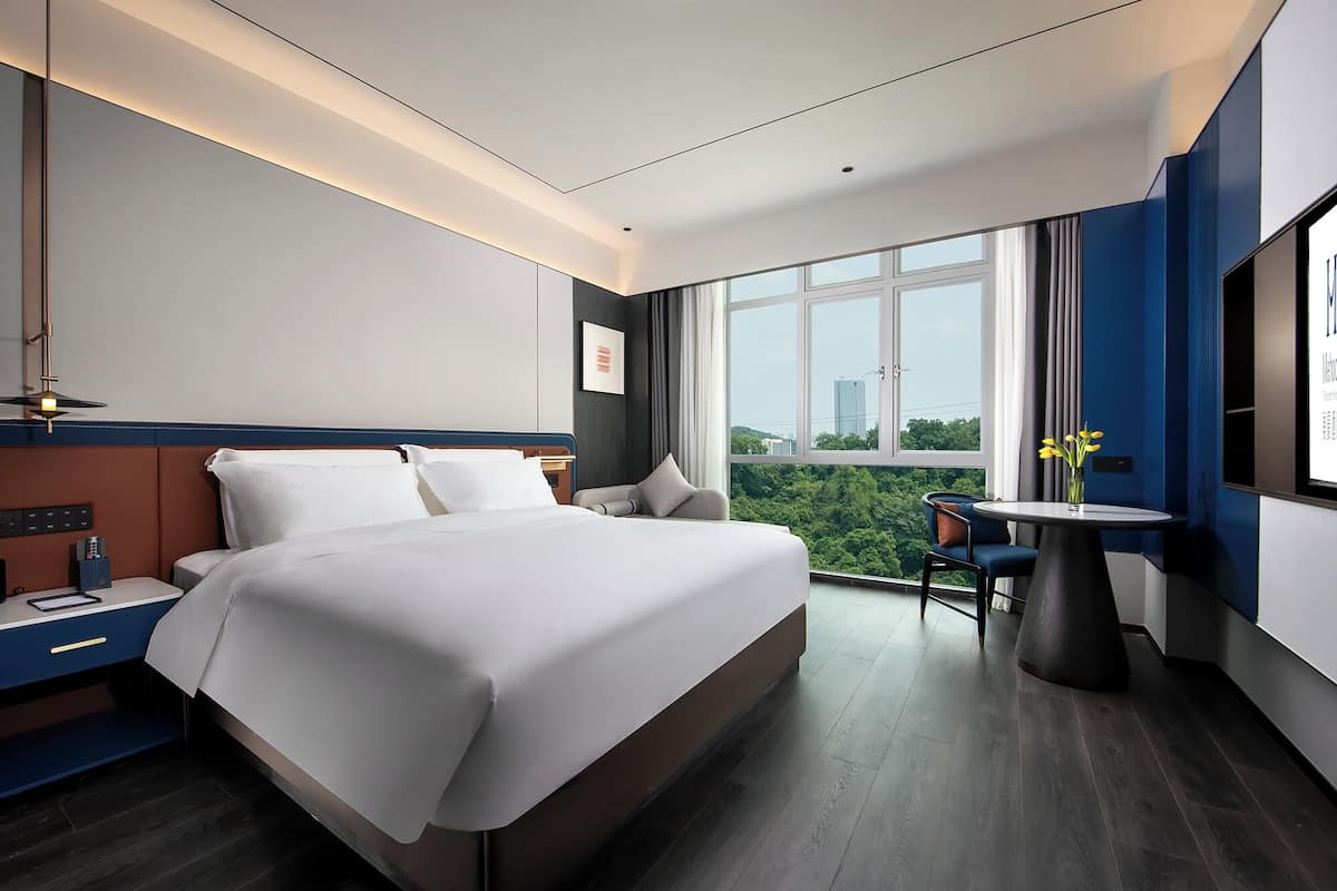 Habitación de hotel moderna con una cama grande, un escritorio y vistas a la ciudad.