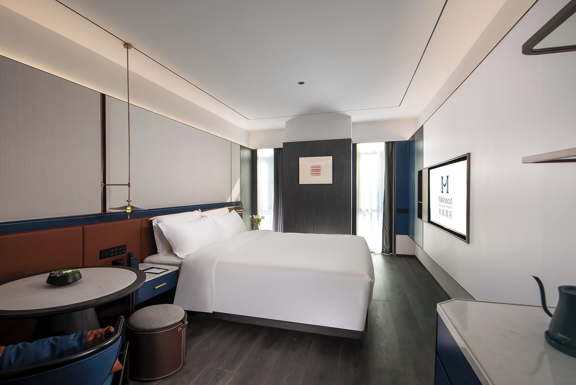 A hotel room with a bed, bedside table, chair, and a small table with a bowl.