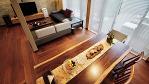 Un salon moderne doté d’un téléviseur à écran plat, d’un canapé et d’un coin repas avec une table et des chaises en bois.