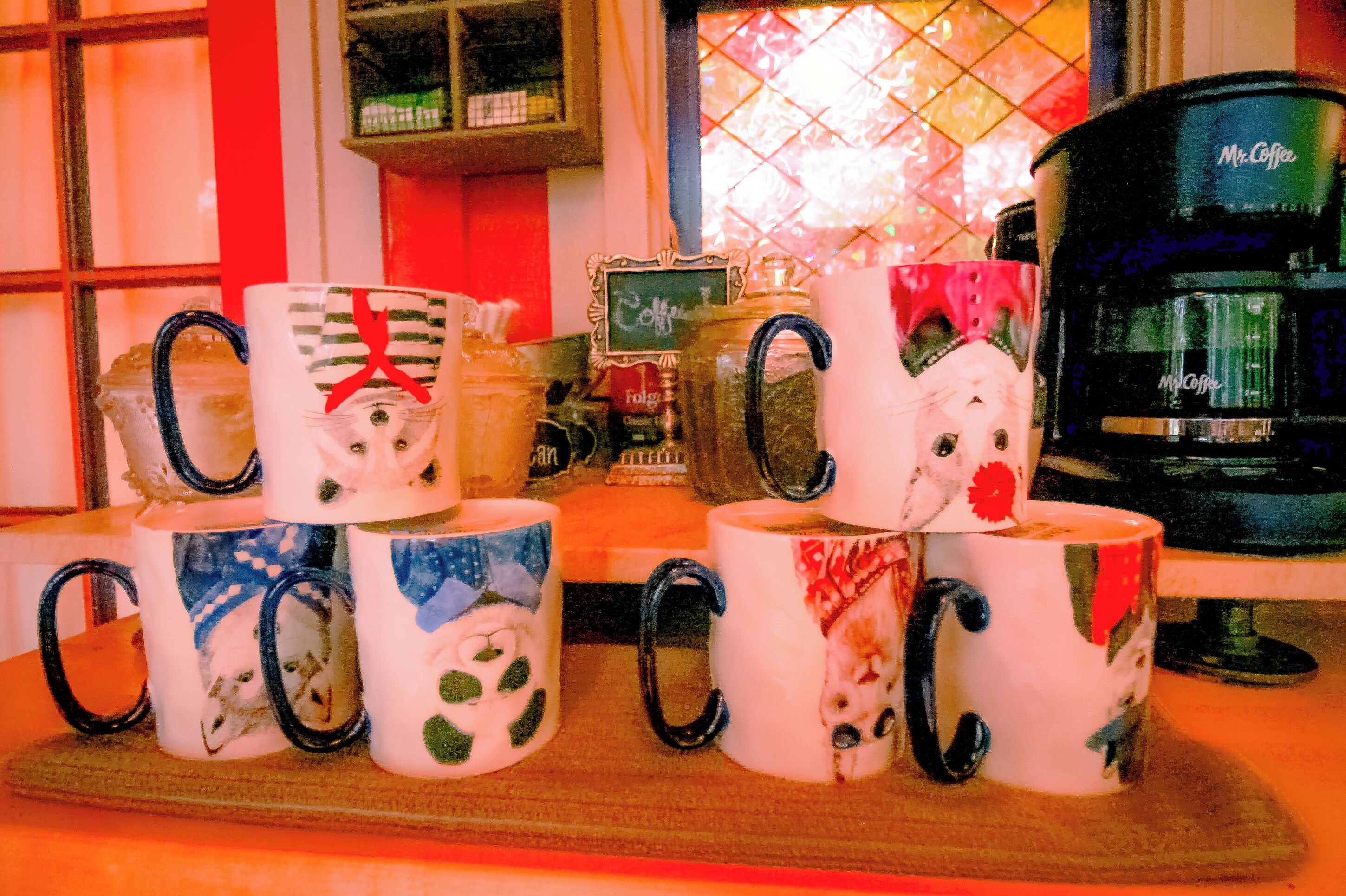 Une collection de tasses à café aux motifs variés, une machine à café et une fenêtre offrant une vue décorative.
