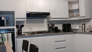 A modern kitchen with white cabinets, a gas stove, a coffee maker, and a microwave. - Envigado: Tradición y Modernidad (Envigado)