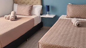 A bedroom with two beds, each with a beige quilted bedspread and rolled towels. - Envigado: Tradición y Modernidad (Envigado)