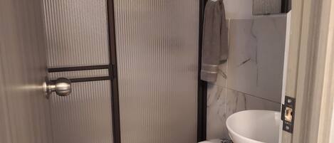 A bathroom with a toilet, a sink, and a mirror.