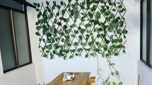 A wooden picnic table with benches, a green artificial turf floor, and a wall-mounted climbing plant. - Envigado: Tradición y Modernidad (Envigado)