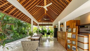 Una hall d'albergo moderna con soffitto in legno, una reception e un'area salotto con sedie e tavoli.