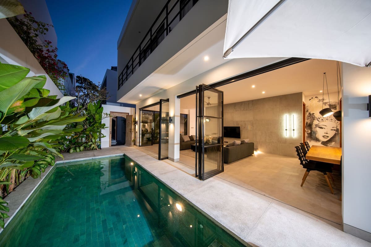 Ein modernes Haus mit Swimmingpool, Schiebetüren und einem Essbereich.