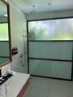 A modern bathroom with a glass shower enclosure, a marble sink, and a large mirror.
