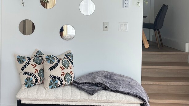 Un salon moderne avec un banc, des miroirs décoratifs et des plantes fixées au mur.