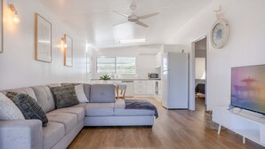 A modern living room with a grey sectional sofa, a flat-screen TV, and a ceiling fan. - Welcome to - Family Tides! (Mulambin)