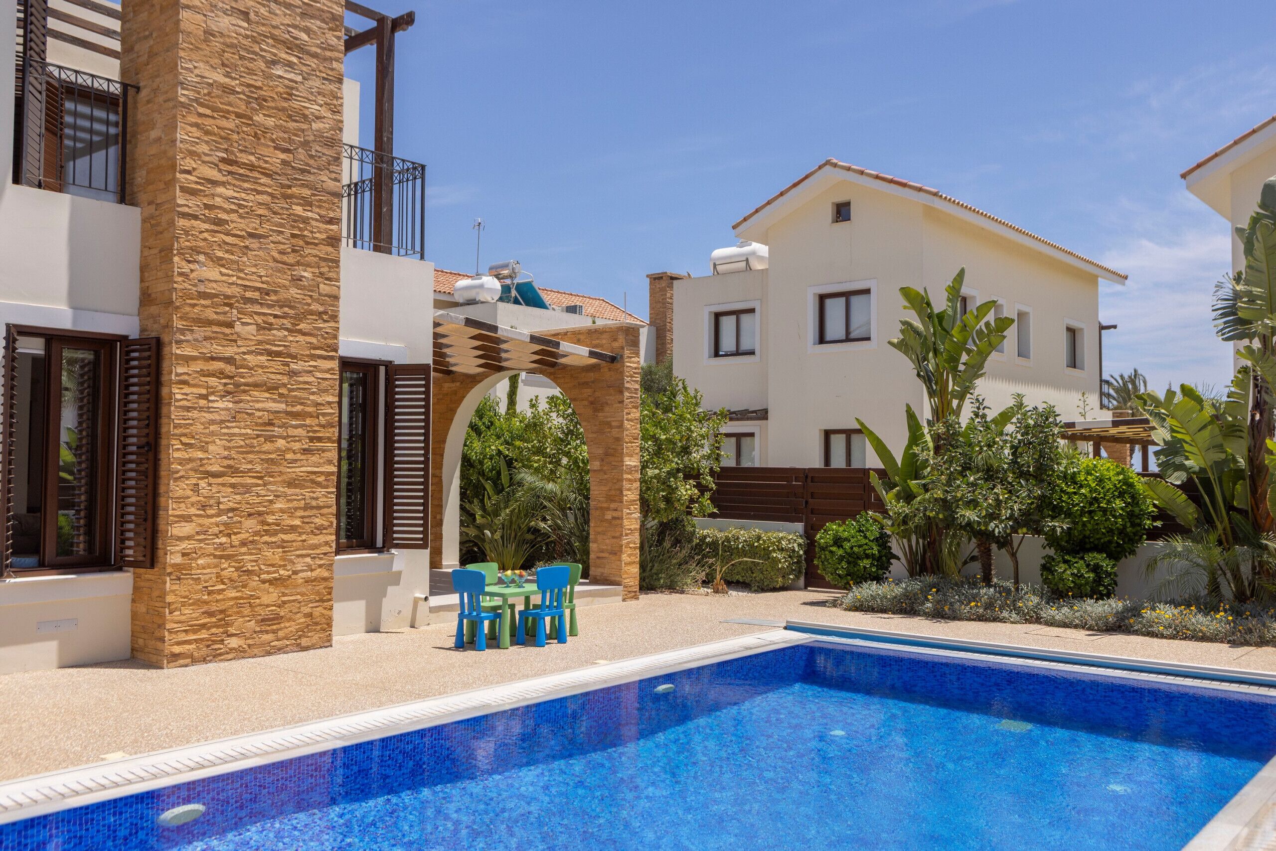 A modern building with a swimming pool, outdoor seating, and a stone facade.