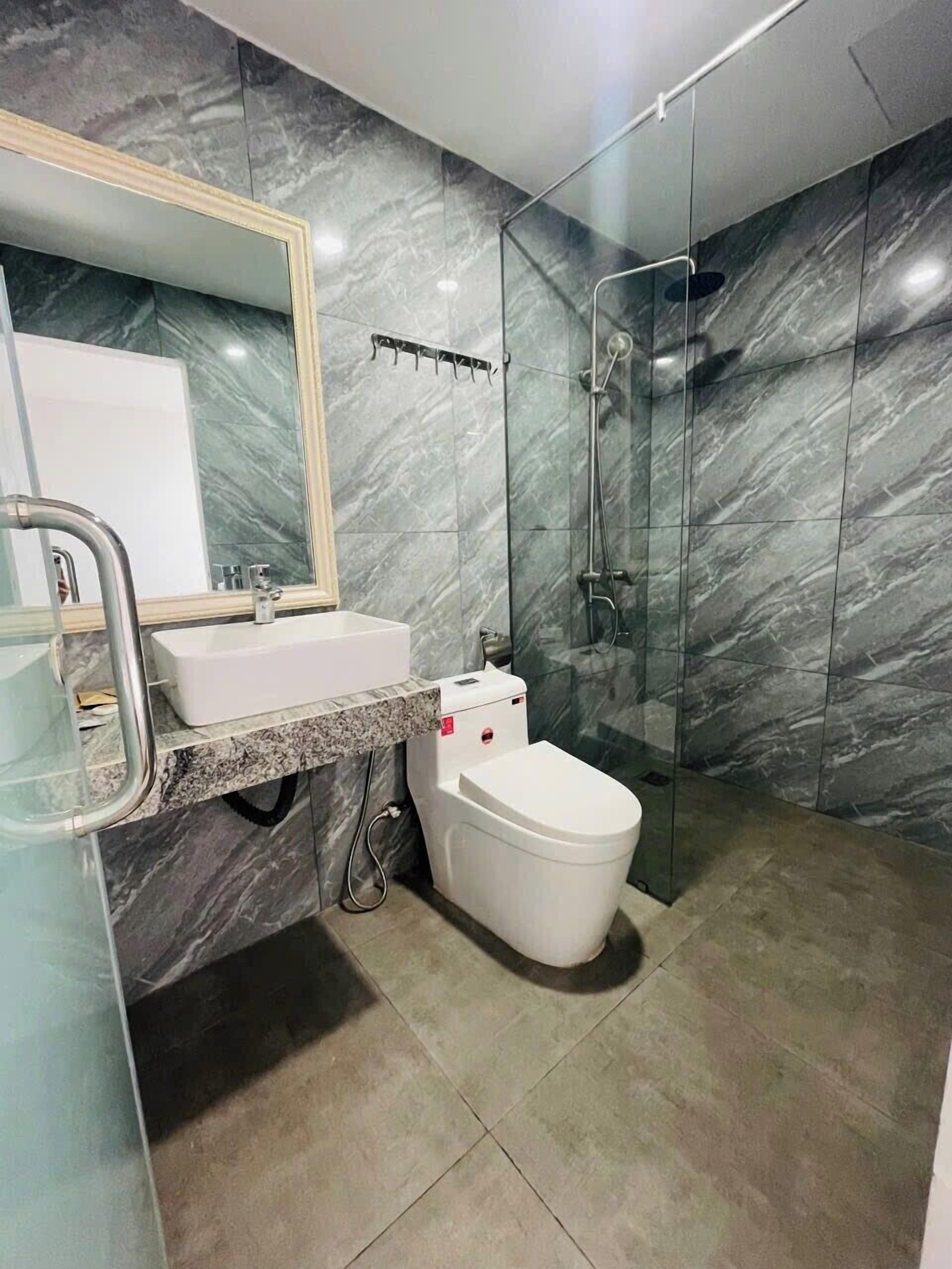 A modern bathroom with a marble backsplash, a glass shower enclosure, and a white toilet.