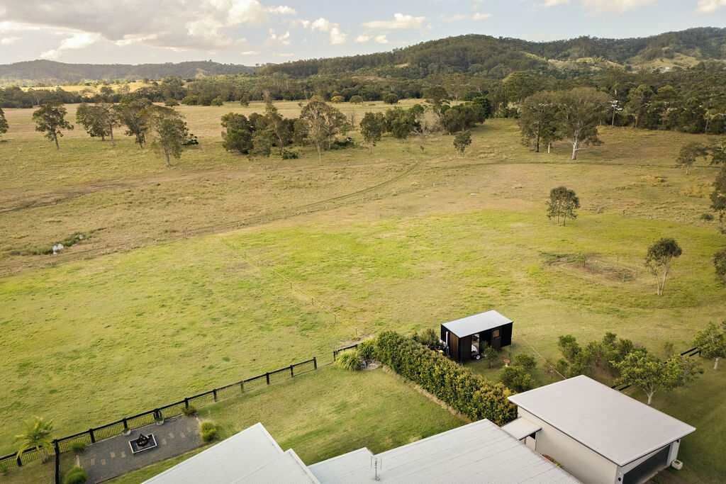 A rural landscape with a small building surrounded by open fields and scattered trees.