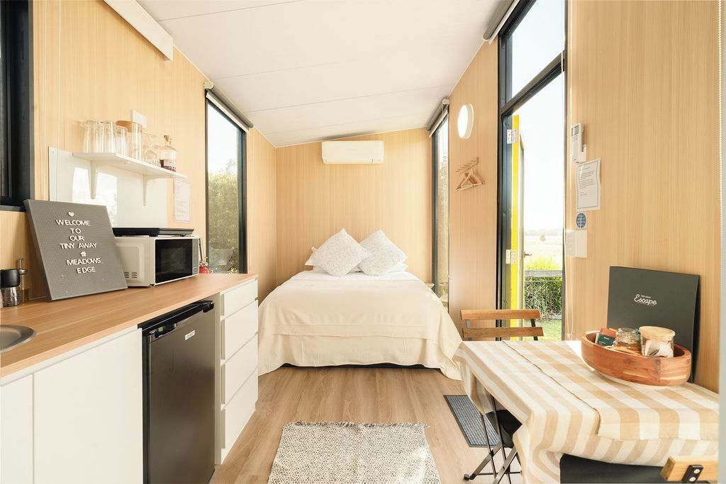 Una habitación funcional con cama, kitchenette y un pequeño comedor.