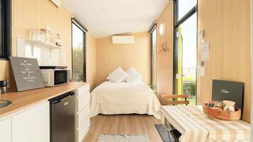 Una habitación funcional con cama, kitchenette y un pequeño comedor.
