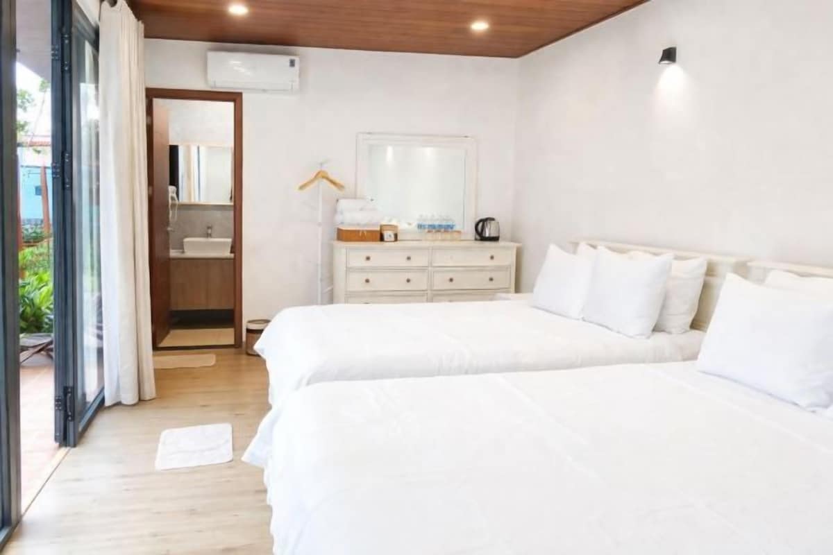 A bedroom with two beds, a dresser, a mirror, and an air conditioning unit.