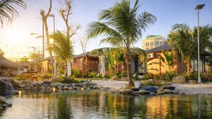 Een resort met een zwembad, palmbomen en een gebouw met de tekst 'The Rebirth'.