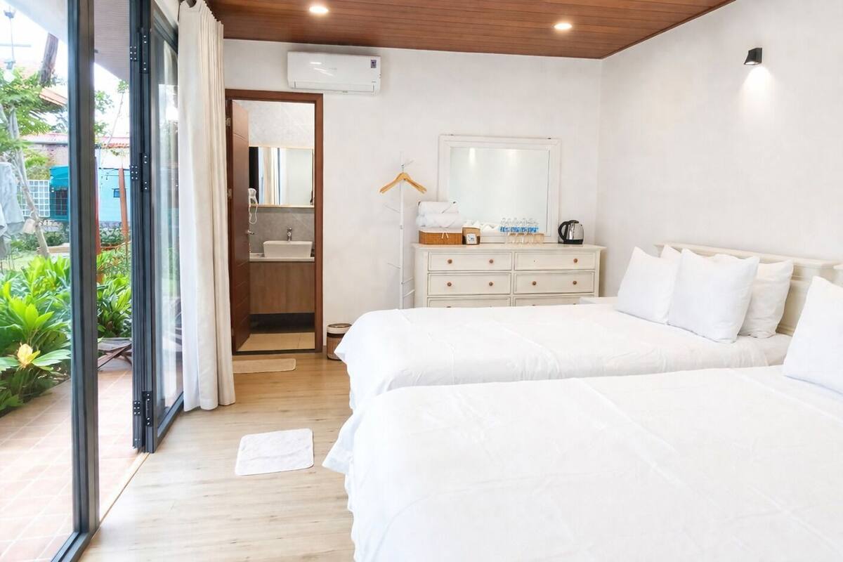 Une chambre avec deux lits, une commode, un miroir et un appareil de climatisation.