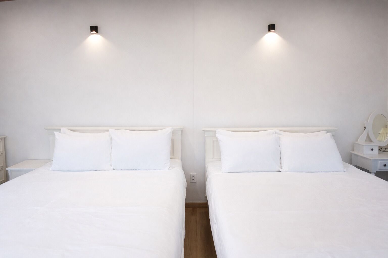 A double room with two beds, each with white bedding and headboards, and bedside tables with lamps.