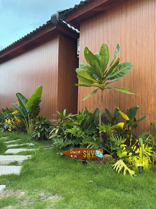 A garden with various plants and a wooden building in the background. - Melaka Ho Tram - Beachside Bungalows (Ho Chi Minh City)