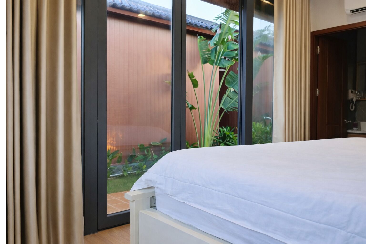 Quarto com uma grande janela, uma cama e vista para um jardim.