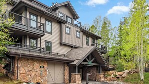 A modern two-story building with a stone facade, a balcony, and a gated entrance.