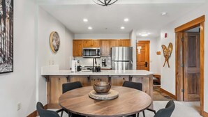 A modern kitchen with wooden cabinets, stainless steel appliances, and a central island with a round table and chairs.