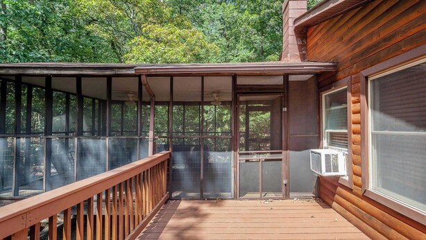 Une terrasse en bois avec une enceinte en verre, une porte et un appareil de climatisation.