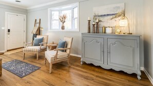 A room with a wooden floor, a grey cabinet, and a painting above it.