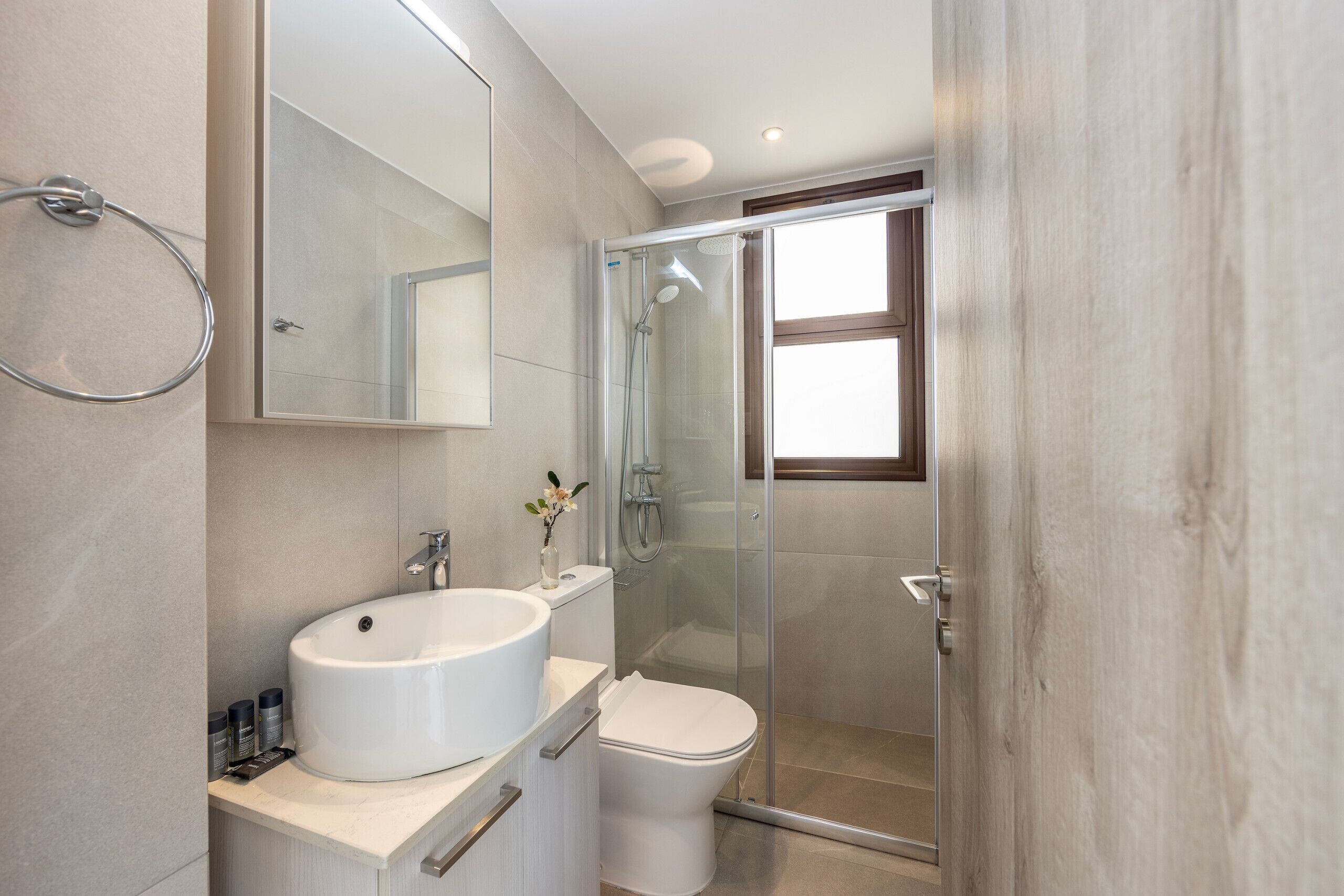Een moderne badkamer met een douche met glazen wand, een wit wastafelmeubel en een toilet.