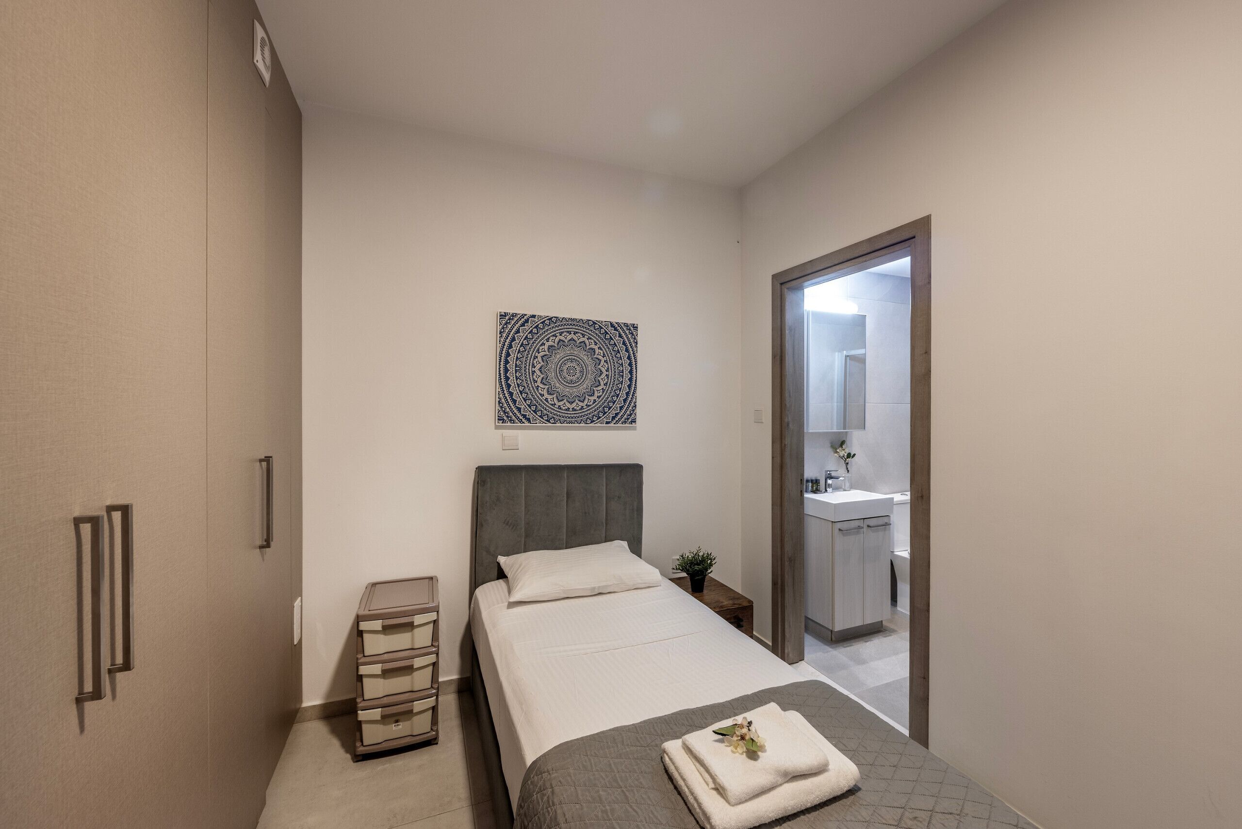 A bedroom with a bed, bedside table, and a wall-mounted artwork.