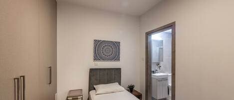 A bedroom with a bed, bedside table, and a wall-mounted artwork.