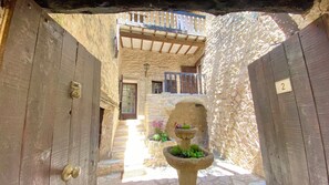 A narrow stone corridor with wooden doors and a small fountain. - La Mistraline Village House, in the Heart of Luberon, Provence! (Caseneuve)