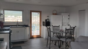 A compact kitchen with a dining area, a large window, and a view of the outdoors. - Hidden Haven: Open Concept Inside, Dramatic Views Outside (Questa)