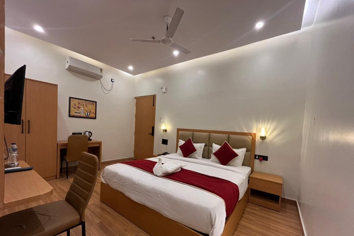 A hotel room with a bed, desk, chair, and a ceiling fan.