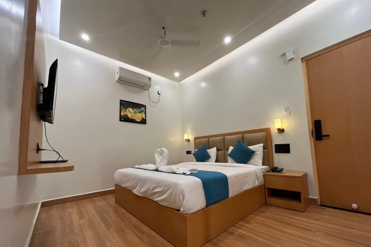 A modern hotel room with a large bed, bedside tables, a TV mounted on the wall, and a ceiling fan.