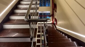 Eine moderne Treppe mit Metallgeländer, Marmorstufen und Blick auf einen Raum mit Fenster und roter Wand.