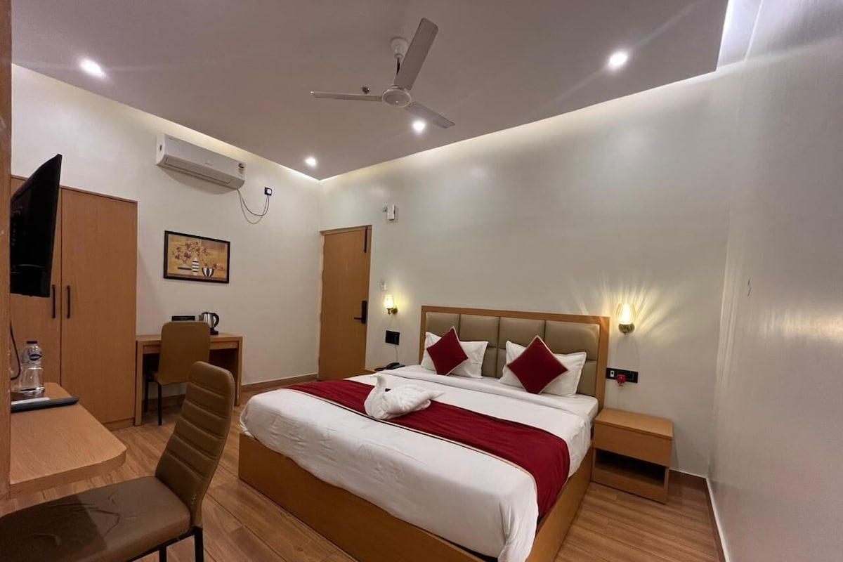 A hotel room with a bed, desk, chair, and a ceiling fan.