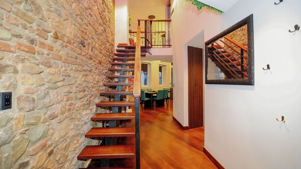 A staircase with wooden steps and a stone wall, leading to a dining area with green chairs and a table. - CASA ESMERALDA, Refined duplex 120m2 (Panama)