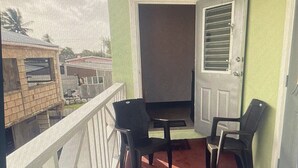 Ein Balkon mit rotem Boden, zwei Stühlen und einer Tür mit Fenster.