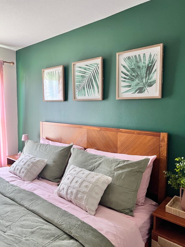 A neatly made bed with green and pink bedding, a wooden headboard, and three framed leaf artworks on a green wall. - Tropical Vacation Home! 3 Rooms, 2 Bedrooms, sleeps 6 ppl. (Ruskin)