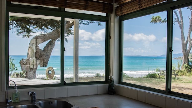 A kitchen with large windows overlooking a beach and ocean.