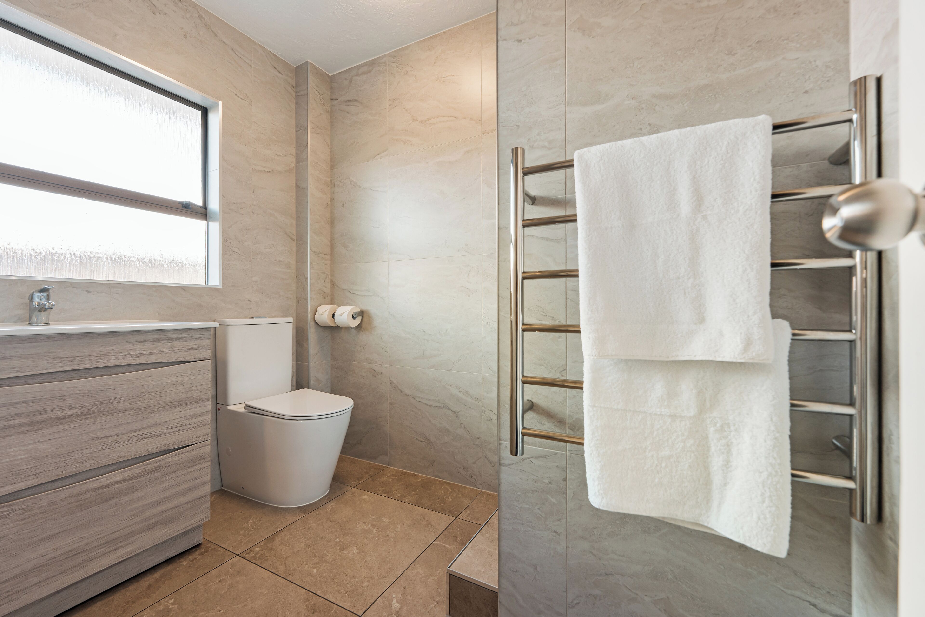 A modern bathroom with a toilet, sink, and towel rack.