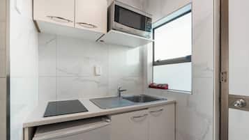 Una cocina compacta con microondas integrado, un lavabo y lavavajillas.