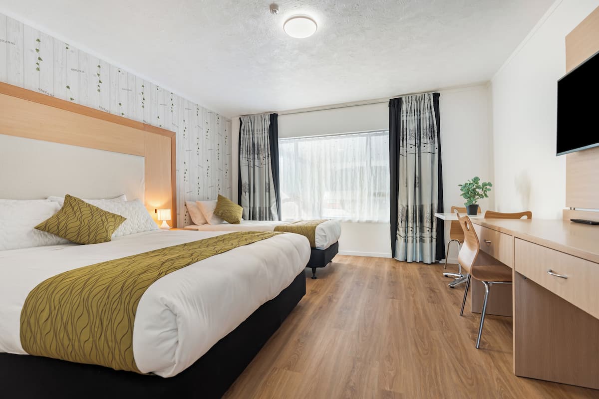 Une chambre d’hôtel avec un grand lit, un bureau, une chaise et un téléviseur.