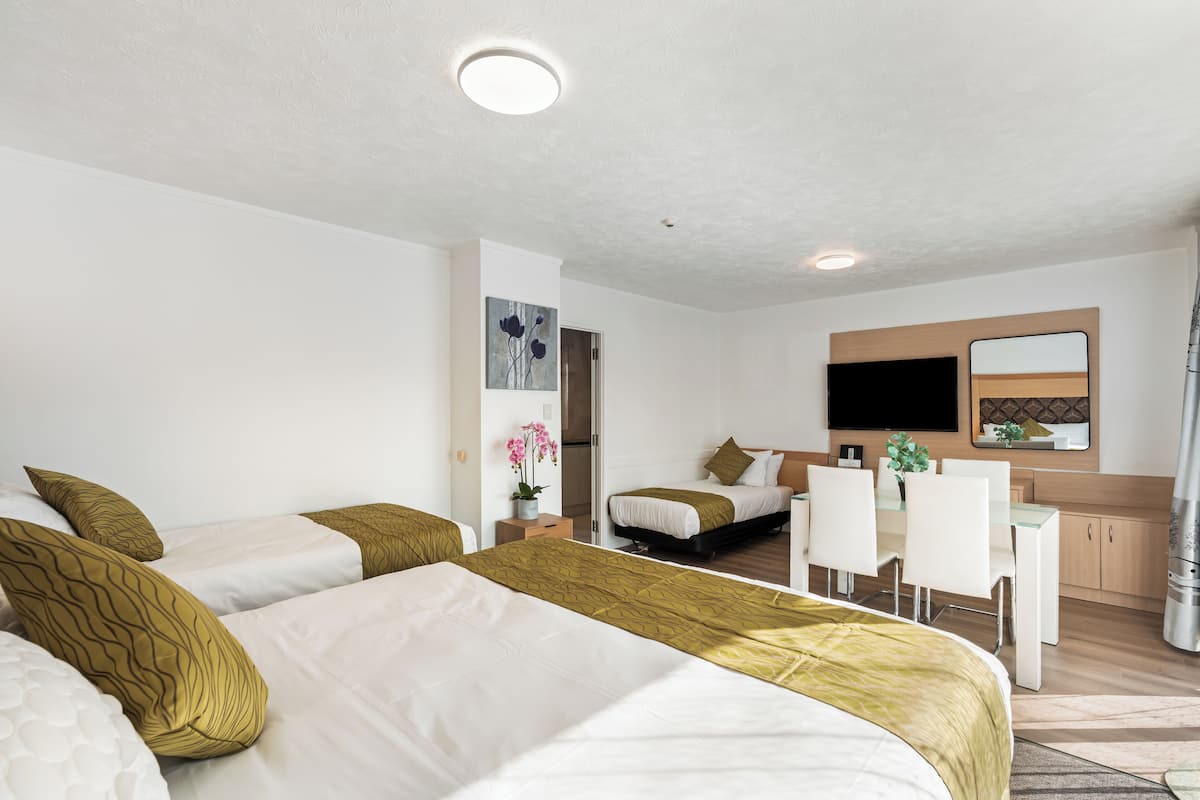 Une chambre d’hôtel avec deux lits, un bureau et une kitchenette.