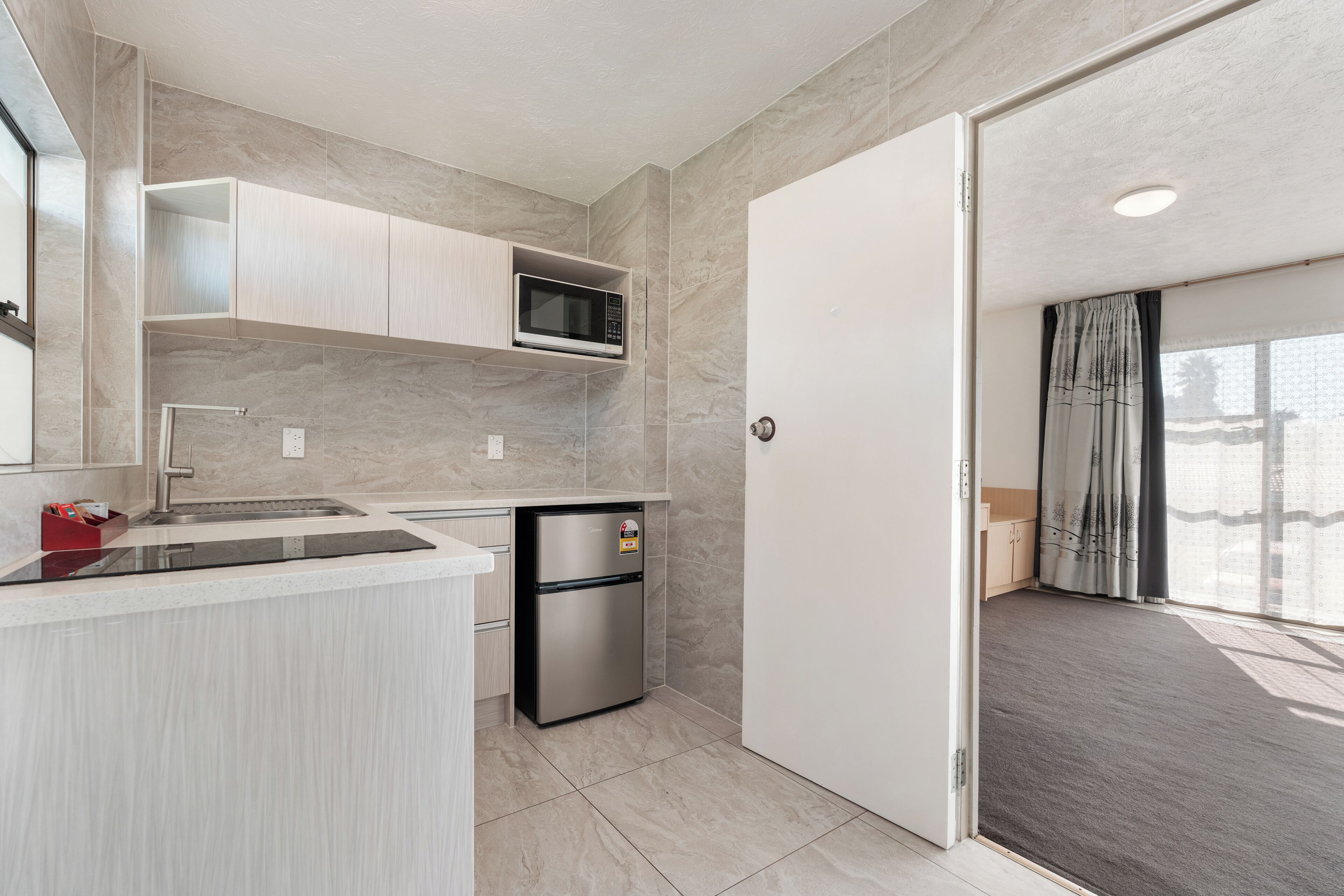 A modern kitchen with a built-in microwave, a refrigerator, and a sink.