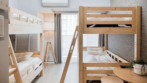 Una habitación compacta y moderna con literas, una mesita pequeña y una planta en maceta.