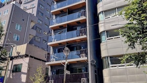 Un edificio de varios pisos con balcones, una clínica dental en la planta baja y un cielo azul despejado al fondo.
