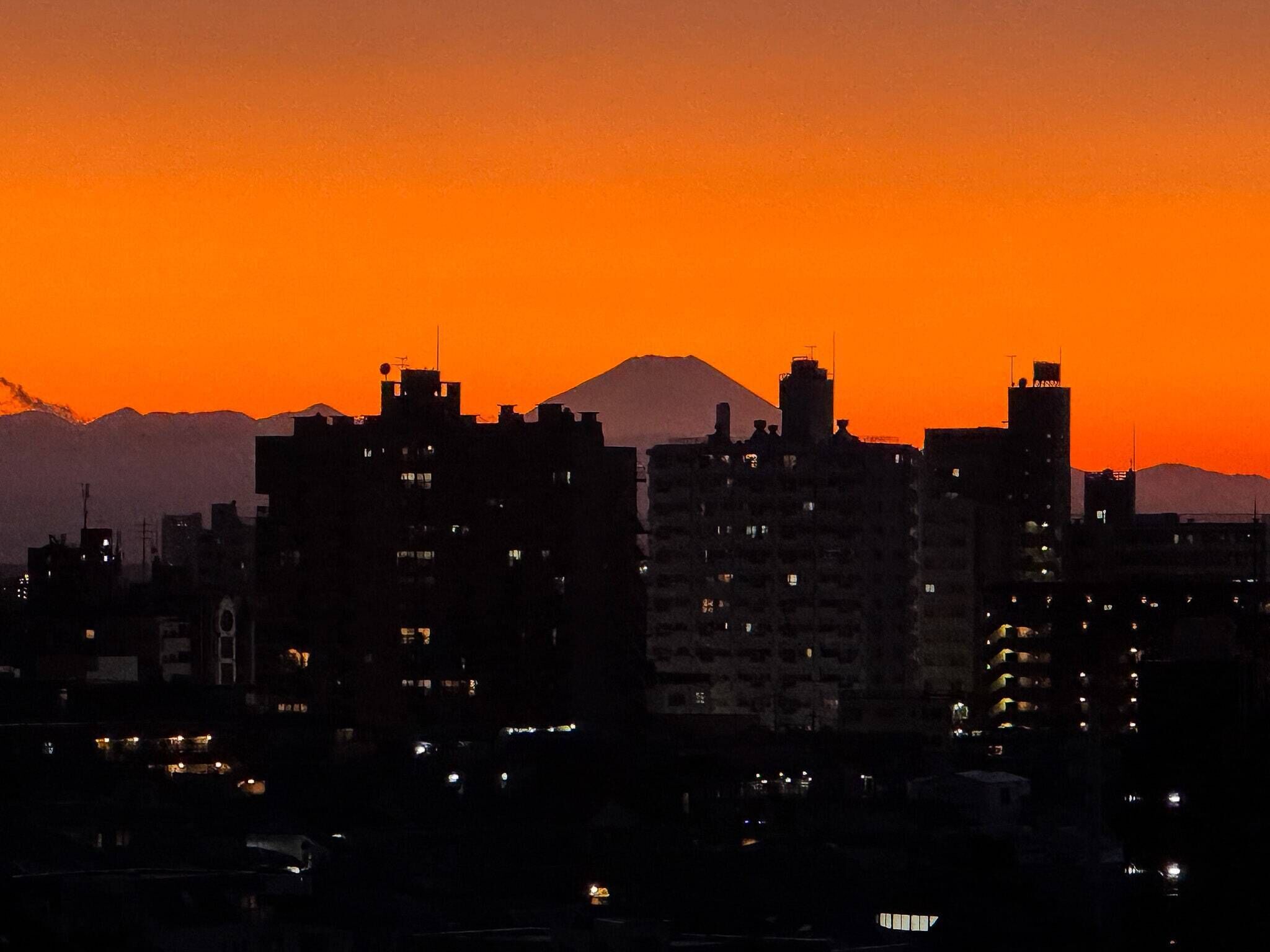A cityscape at dusk with buildings silhouetted against a sunset sky.